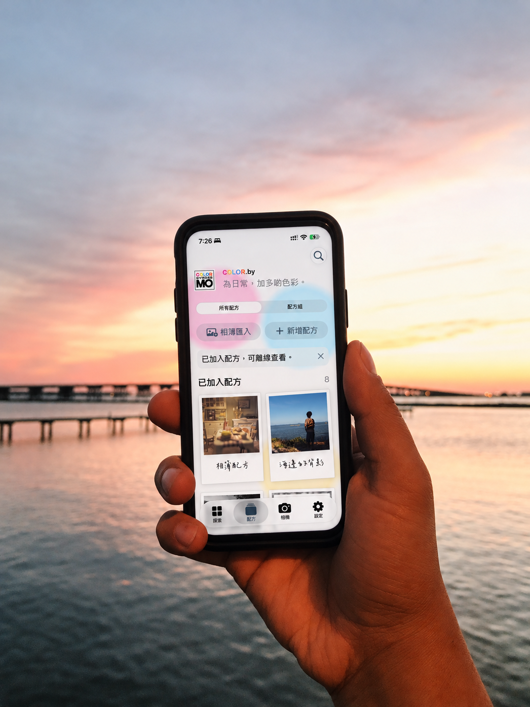 Illustrative mockup of COLOR.by recipes on a handheld phone by the sea at sunset